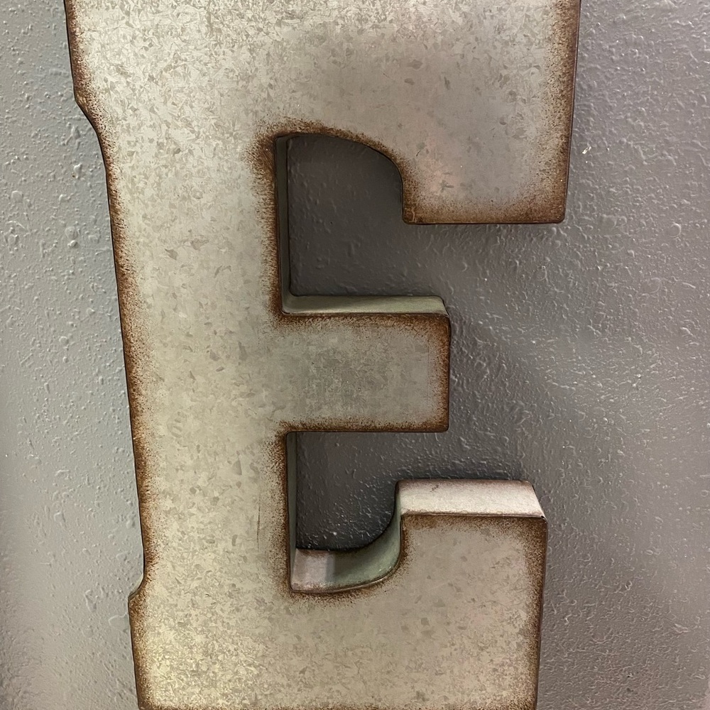 A one if a kind advertisement sign letter “E” made from a tin material.